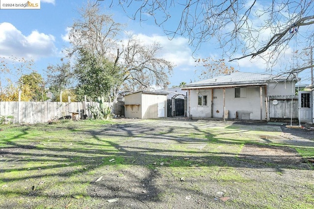 back of property featuring a lawn and a storage shed