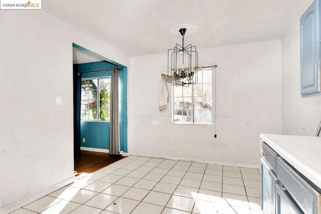 unfurnished dining area featuring light tile patterned floors and an inviting chandelier