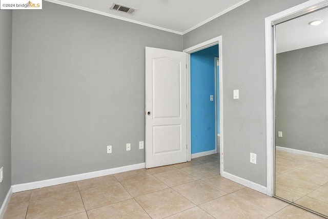 unfurnished bedroom with crown molding, a closet, and light tile patterned floors