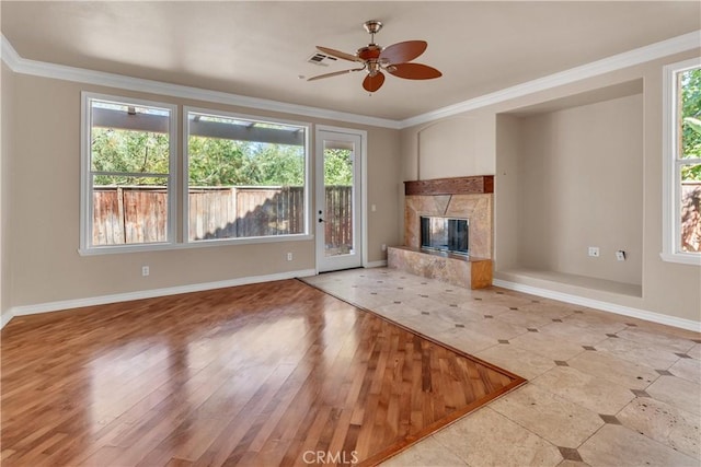 unfurnished living room featuring a high end fireplace, light hardwood / wood-style flooring, ceiling fan, and crown molding