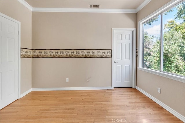 empty room featuring crown molding, light hardwood / wood-style flooring, and a healthy amount of sunlight