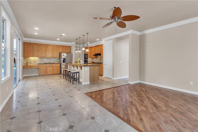 kitchen featuring a breakfast bar, a center island, backsplash, crown molding, and light hardwood / wood-style flooring