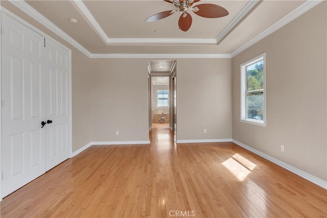 spare room featuring ceiling fan, light hardwood / wood-style floors, ornamental molding, and a tray ceiling