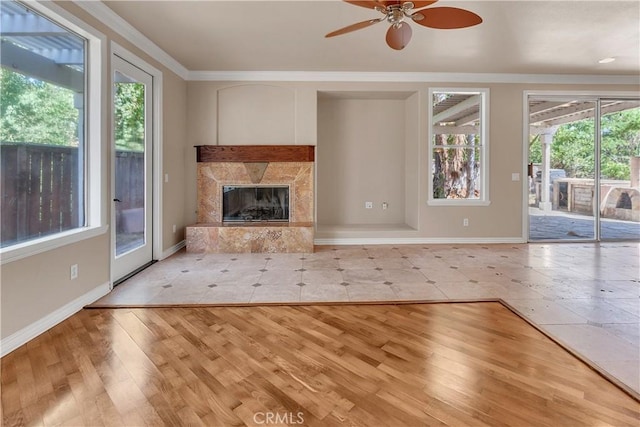 unfurnished living room featuring a fireplace, light wood-type flooring, a wealth of natural light, and ceiling fan