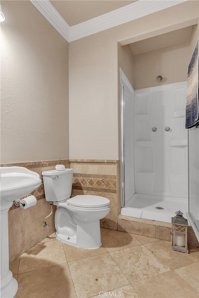 bathroom featuring tile patterned floors, walk in shower, crown molding, tile walls, and toilet