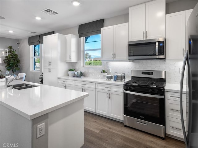 kitchen featuring white cabinetry, sink, stainless steel appliances, dark hardwood / wood-style flooring, and decorative backsplash