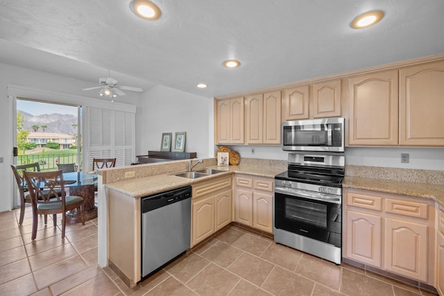 kitchen featuring kitchen peninsula, stainless steel appliances, sink, and ceiling fan