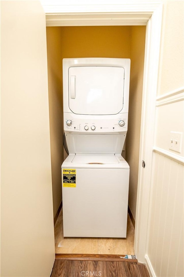 washroom with stacked washer and dryer and hardwood / wood-style floors