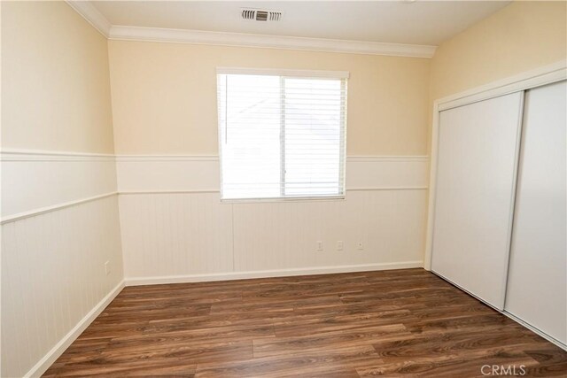 unfurnished bedroom featuring dark hardwood / wood-style flooring, a closet, and crown molding