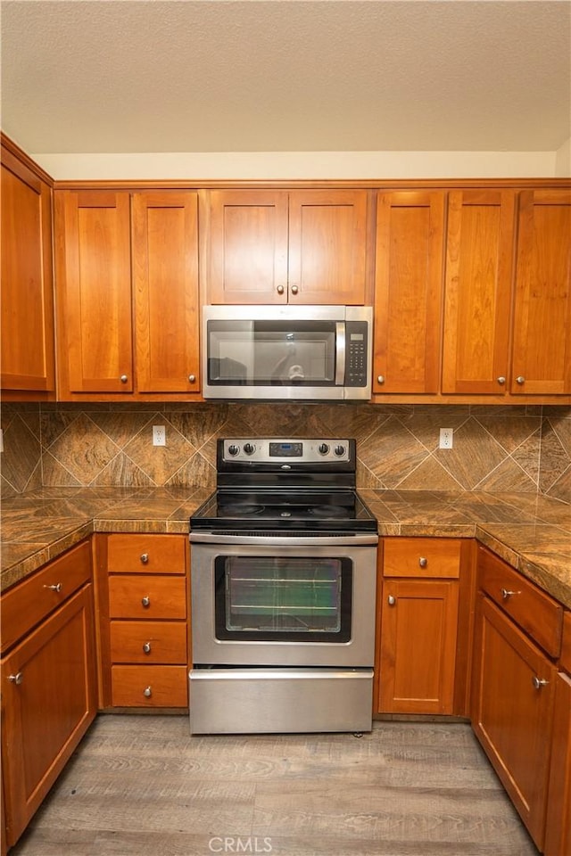 kitchen with tasteful backsplash, light wood-type flooring, and appliances with stainless steel finishes