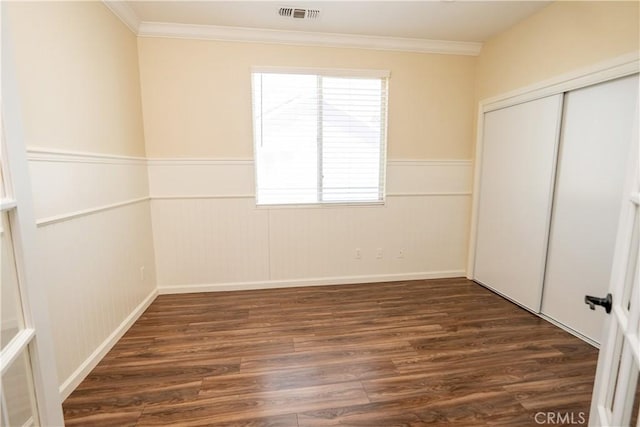 unfurnished bedroom featuring crown molding, a closet, and dark wood-type flooring