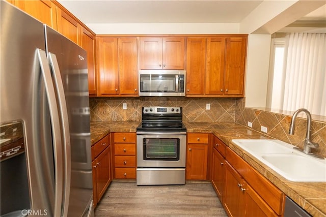 kitchen featuring backsplash, sink, stainless steel appliances, and light hardwood / wood-style flooring