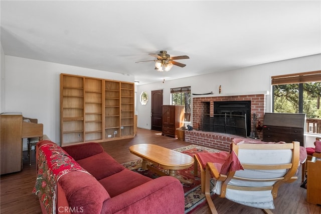 living room with dark wood-type flooring, a brick fireplace, and ceiling fan