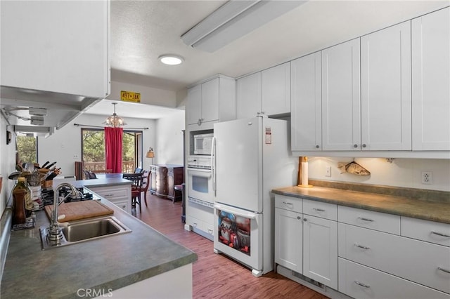 19680 Sugarwood Ct, Hidden Valley Lake, CA 95467 - kitchen featuring white cabinets, light wood finished floors, an inviting chandelier, white appliances, and a sink