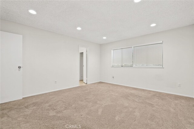 unfurnished room featuring light carpet and a textured ceiling