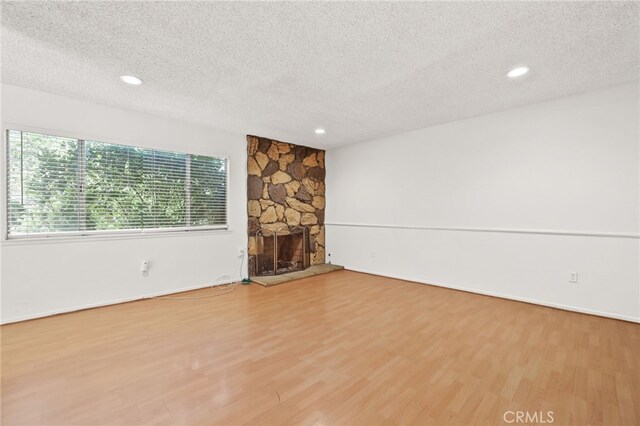 unfurnished living room with a fireplace, a textured ceiling, and hardwood / wood-style flooring