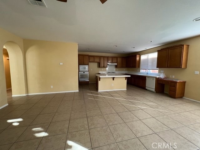 kitchen featuring white appliances, a kitchen island, light tile patterned floors, ceiling fan, and sink