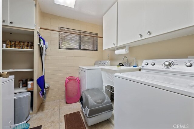 washroom featuring light tile patterned flooring, washer and dryer, and cabinets