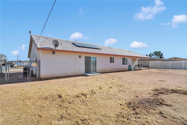 rear view of property featuring solar panels