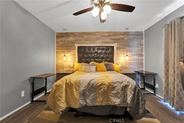 bedroom with dark wood-type flooring, ceiling fan, and wooden walls