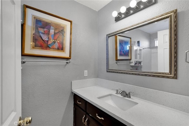 bathroom with a textured wall and vanity