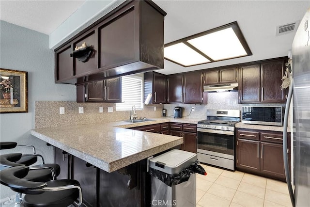 kitchen featuring appliances with stainless steel finishes, sink, a kitchen bar, light tile patterned floors, and kitchen peninsula