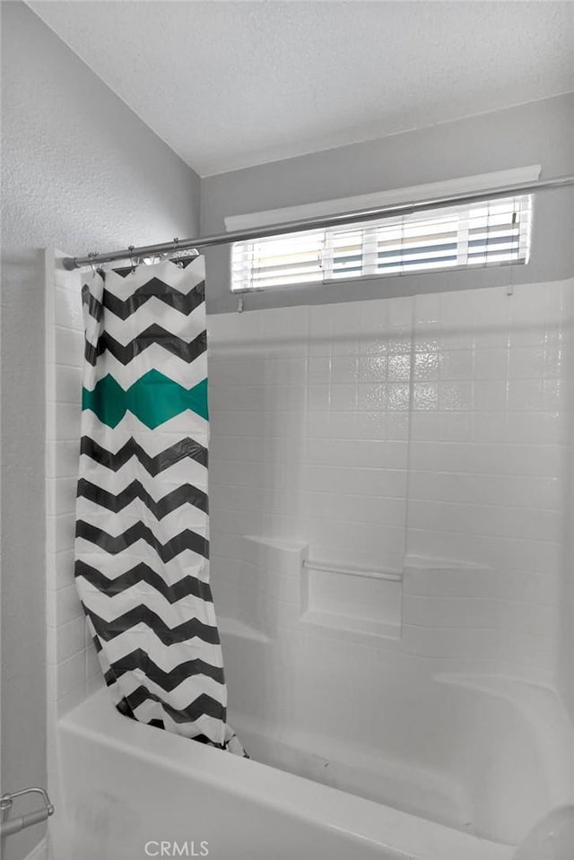 bathroom featuring a wealth of natural light, a textured ceiling, and shower / bath combo with shower curtain