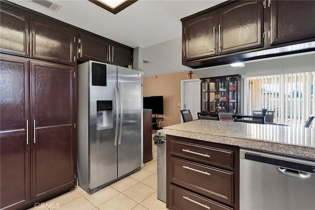 kitchen with dark brown cabinetry, light tile patterned floors, and stainless steel appliances