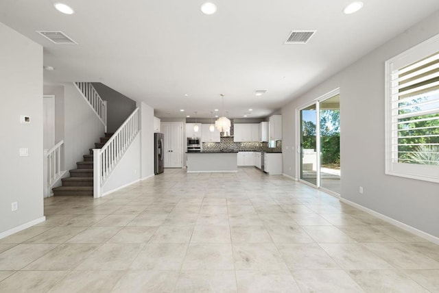 unfurnished living room featuring light tile patterned floors and an inviting chandelier