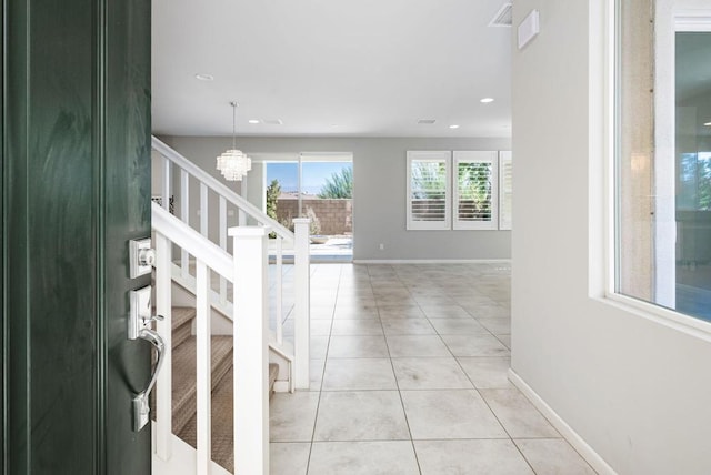 corridor featuring light tile patterned flooring and a notable chandelier