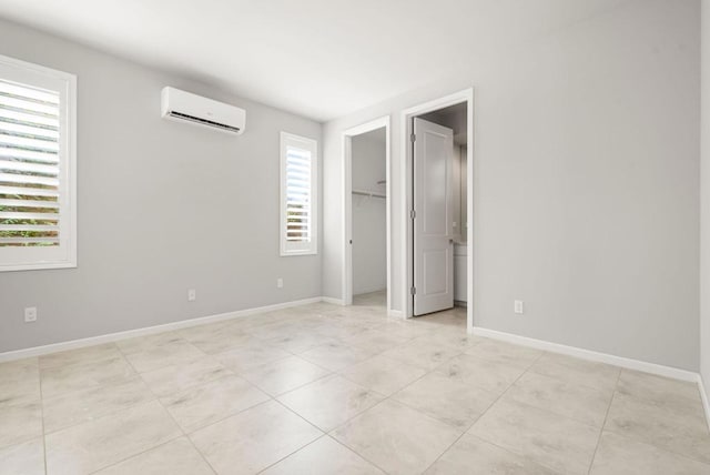 unfurnished bedroom featuring a wall unit AC and a spacious closet