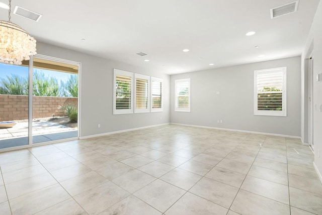 tiled empty room with a wealth of natural light and a chandelier