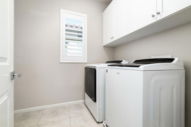 washroom with light tile patterned flooring, washing machine and dryer, and cabinets