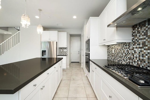 kitchen with wall chimney range hood, white cabinetry, stainless steel appliances, decorative light fixtures, and decorative backsplash