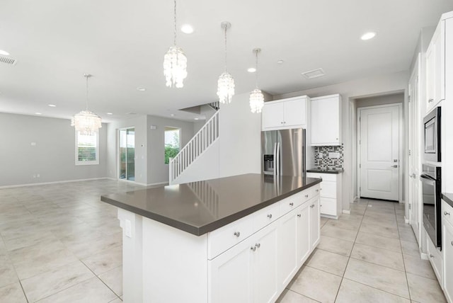 kitchen featuring a kitchen island, appliances with stainless steel finishes, pendant lighting, and white cabinets