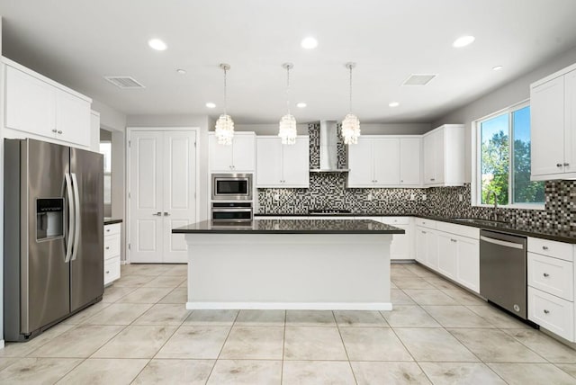 kitchen featuring wall chimney exhaust hood, a kitchen island, hanging light fixtures, and stainless steel appliances