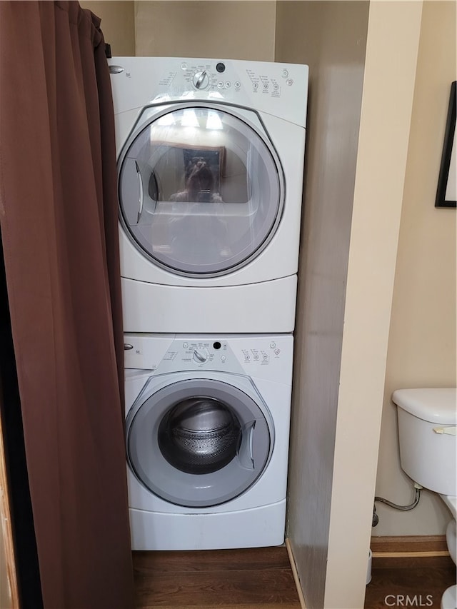 laundry room featuring stacked washer / dryer and dark hardwood / wood-style floors