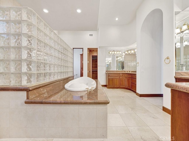 bathroom with tile patterned floors, vanity, and tiled bath