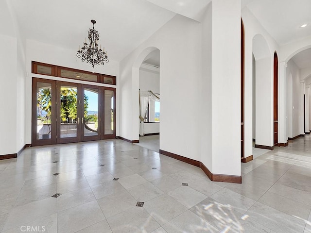 tiled foyer with french doors and a chandelier