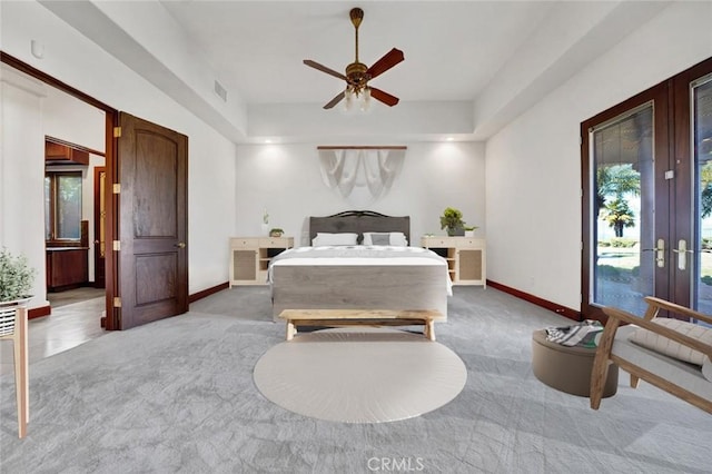 bedroom with a tray ceiling, ceiling fan, french doors, and light carpet