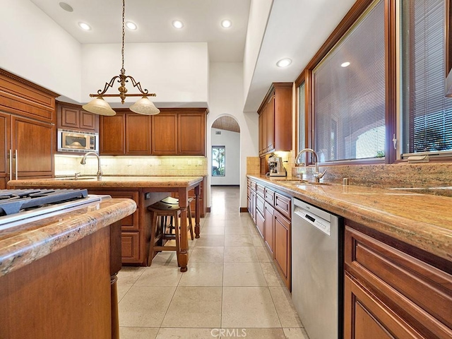 kitchen with built in appliances, sink, light tile patterned floors, and hanging light fixtures