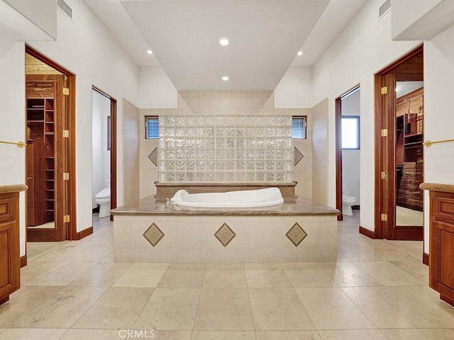 bathroom featuring tiled tub, tile patterned flooring, vanity, and toilet