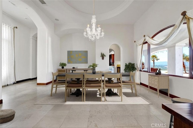 dining area featuring a tray ceiling, a towering ceiling, and an inviting chandelier