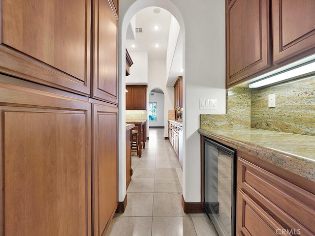 kitchen featuring light stone countertops, light tile patterned floors, tasteful backsplash, and beverage cooler