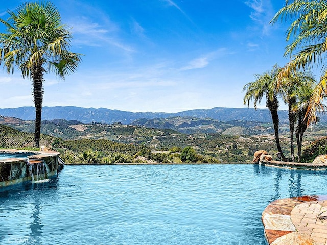 view of swimming pool featuring pool water feature and a water and mountain view