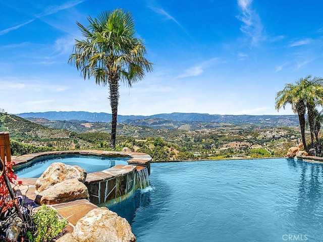 view of swimming pool with pool water feature and a water and mountain view