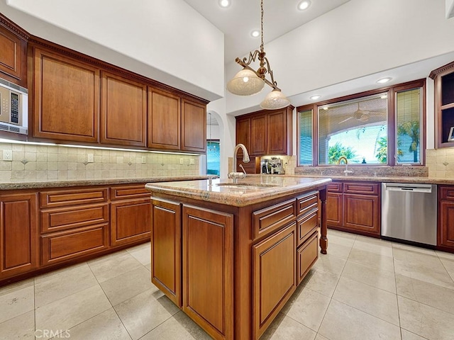 kitchen featuring sink, stainless steel appliances, decorative light fixtures, a kitchen island with sink, and light tile patterned floors