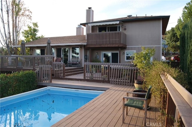 rear view of property featuring a swimming pool side deck and a balcony