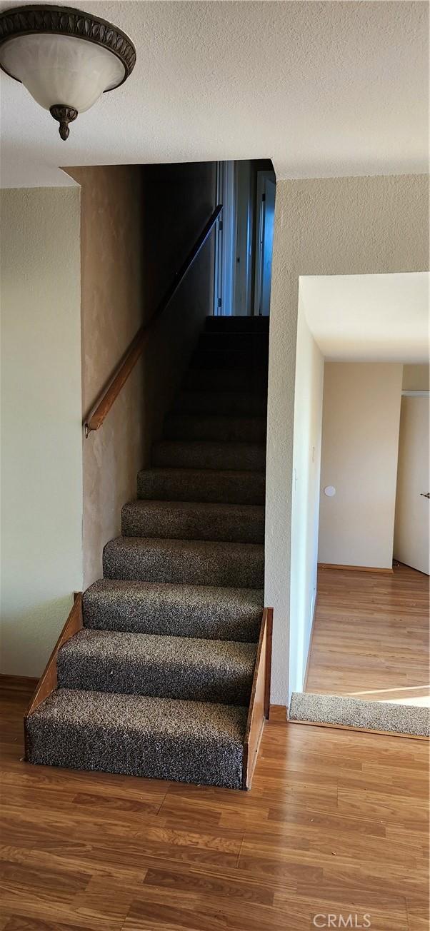 stairs with wood-type flooring and a textured ceiling