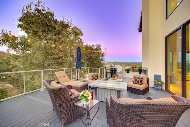 deck at dusk with an outdoor living space with a fire pit